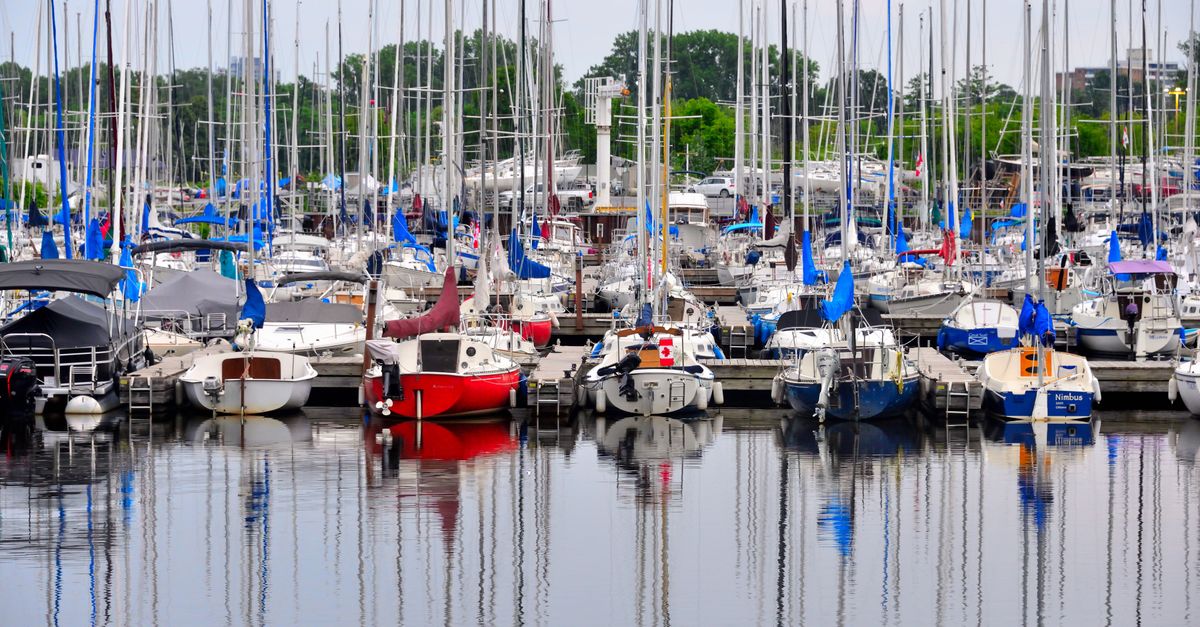 A vibrant marina filled with colorful sailboats and yachts reflected on calm water, perfect for summer travel imagery.